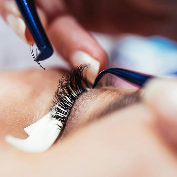 Nahaufnahme eines Auges, an dem künstliche Wimpern angebracht werden