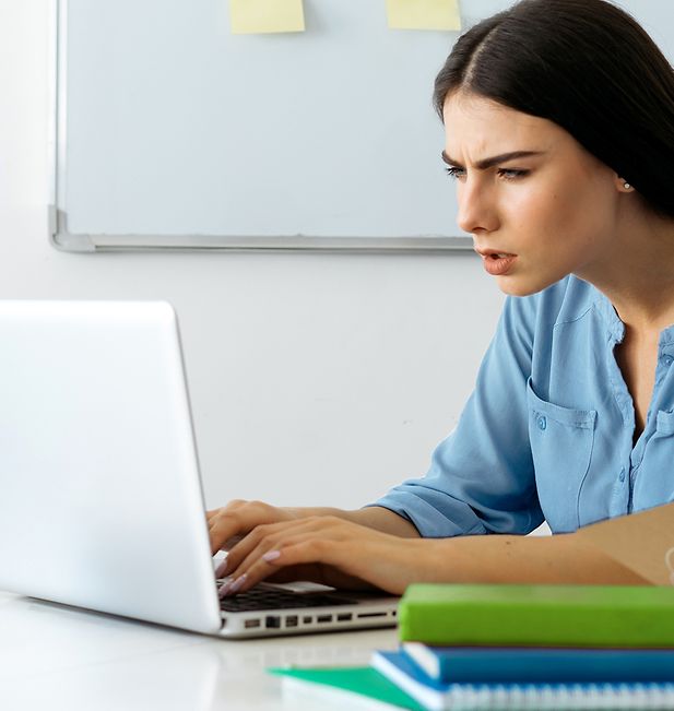 Frau vor einem Computerbildschirm, die die Augen zusammenkneift, weil sie Sehprobleme hat.