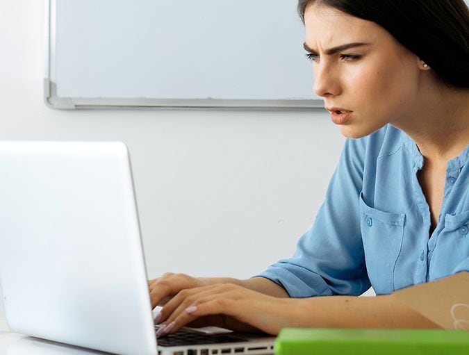 Frau vor einem Computerbildschirm, die die Augen zusammenkneift, weil sie Sehprobleme hat.
