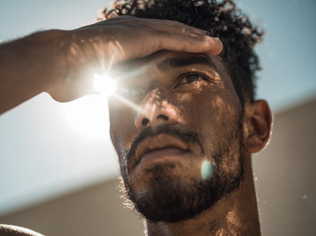 Mann schützt seine Augen vor dem Sonnenlicht